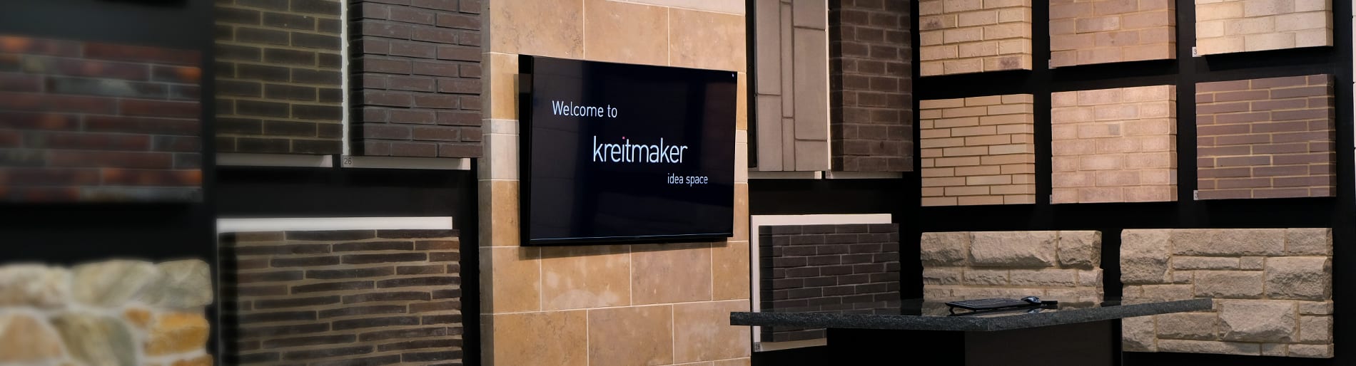 Wall with multiple brick samples and TV screen that says kreitmaker.