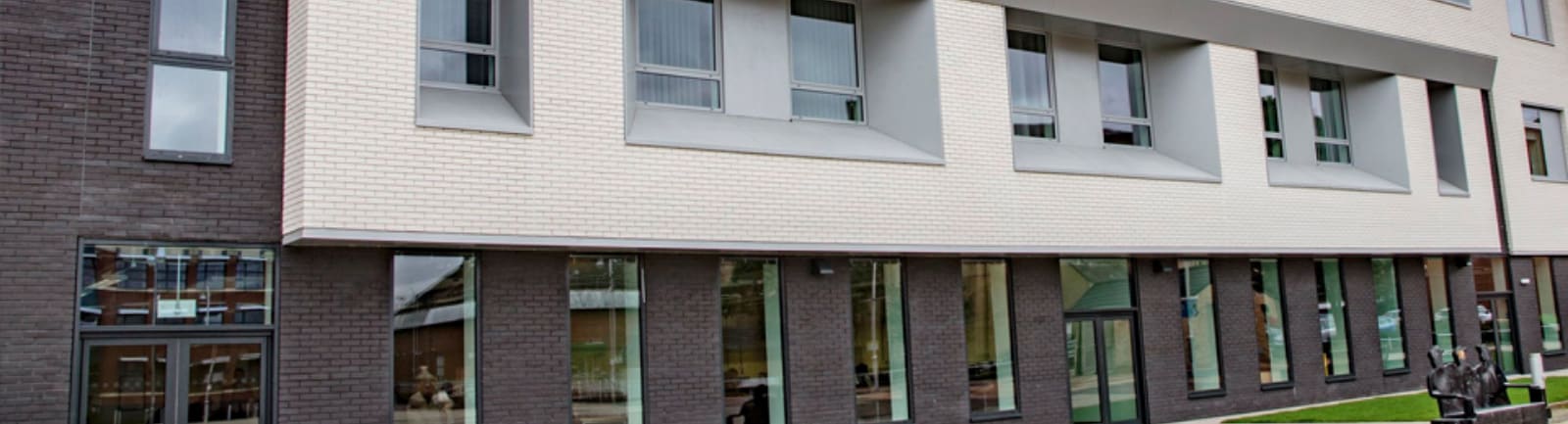 A brick building with two levels and many windows. The top level is white brick and the bottom level is brown.