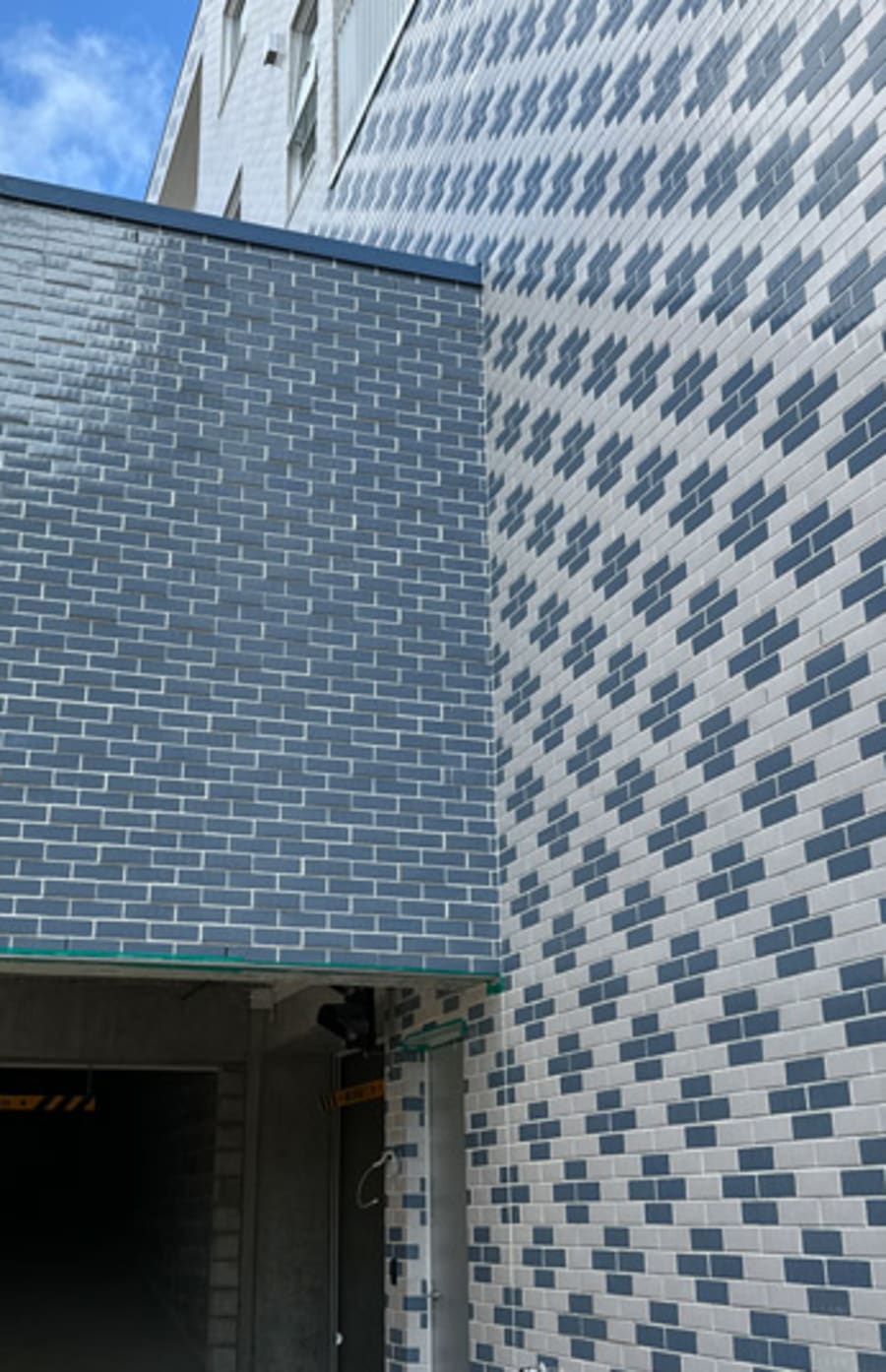 Gery and white patterned brick building with Grey brick overhang.