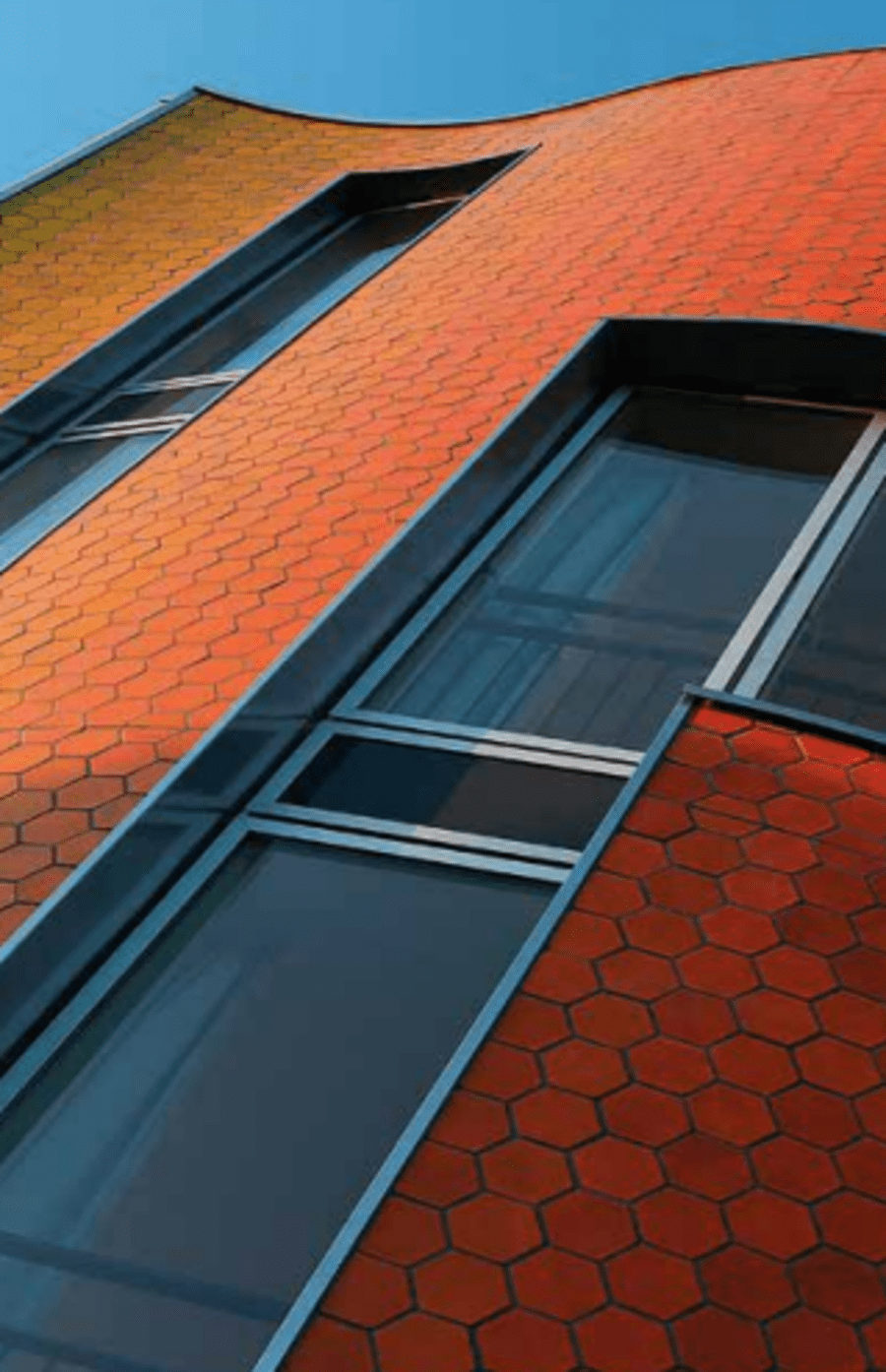 Red and orange glazed brick on the exterior of a building with bricks in an octagonal pattern.