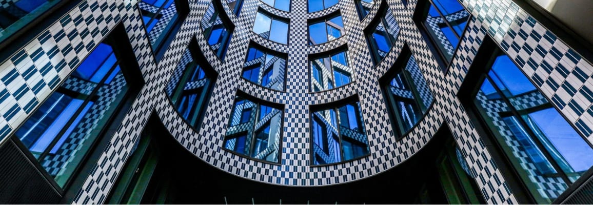 Black and white glazed brick on a curved building with lots of windows.