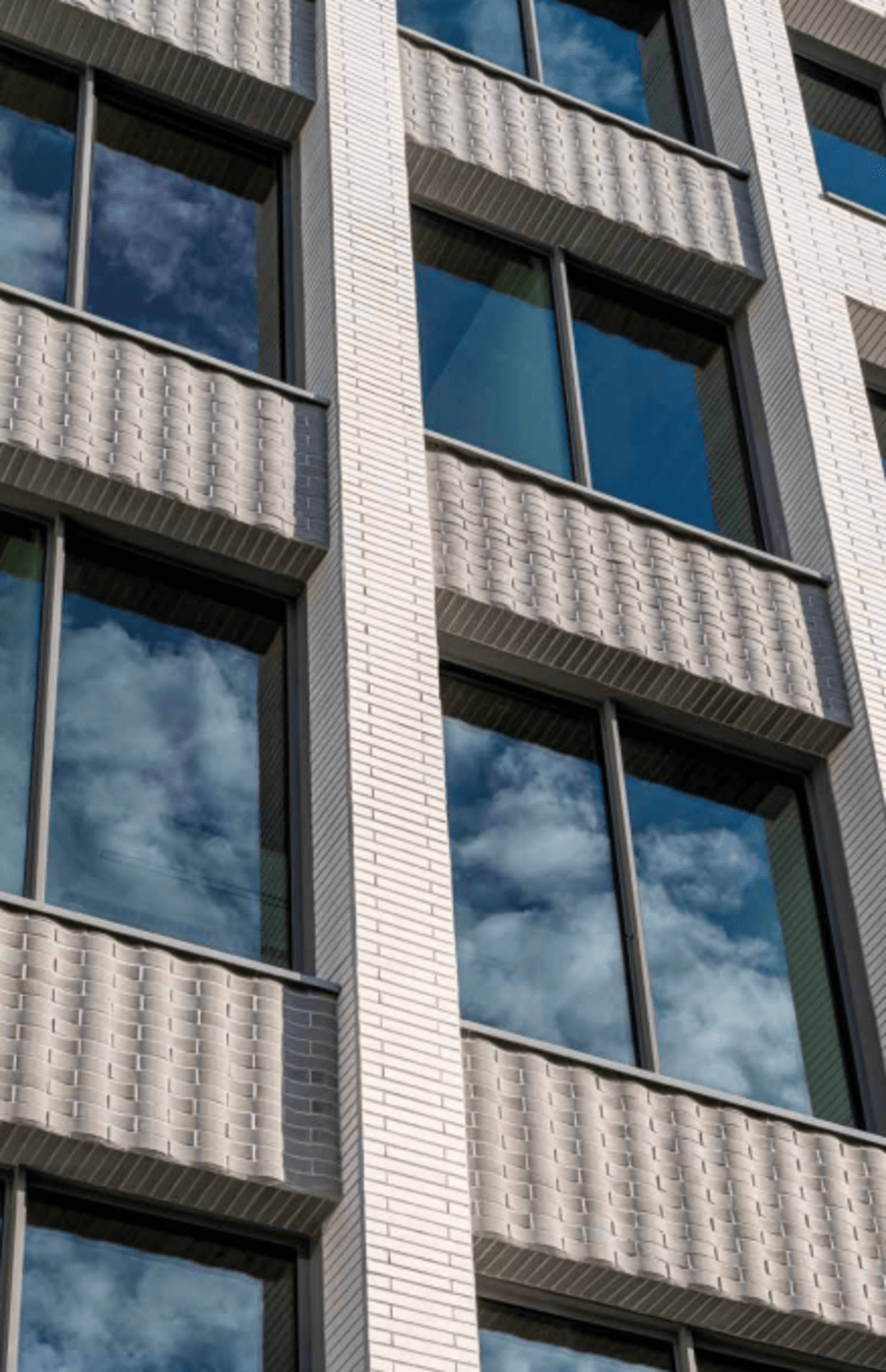 Exterior of a building with light beige brick with a wavy pattern.