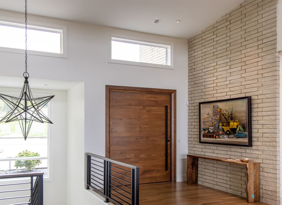 interior of a house with a beige brick wall with a painting next to a wood door and a star shaped chandelier.