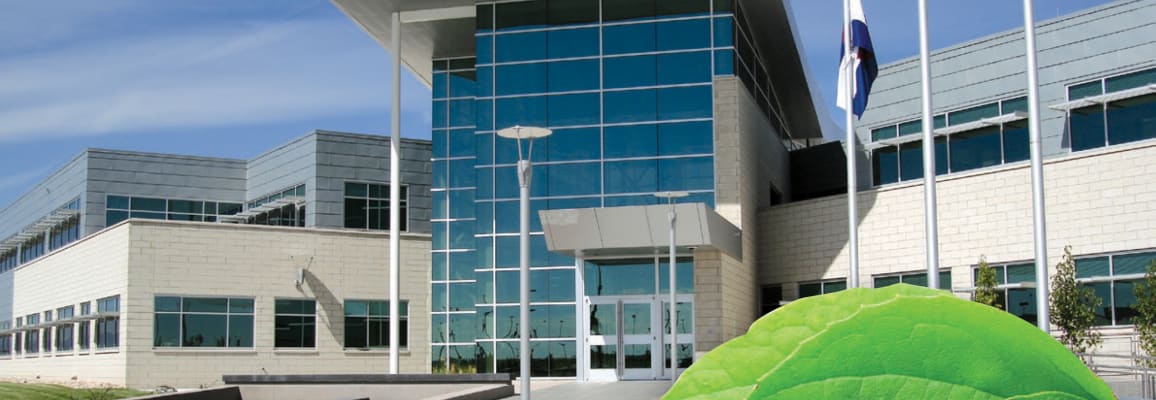 Large building with light brick and flag poles.