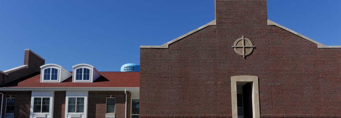 Exterior of large red brick building with circle and cross.