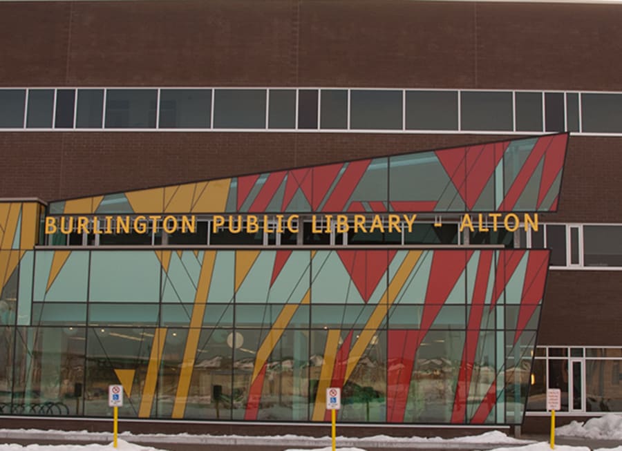 Exterior of Burlington Public Library of Alton with red brick and windows with yellow and red designs.