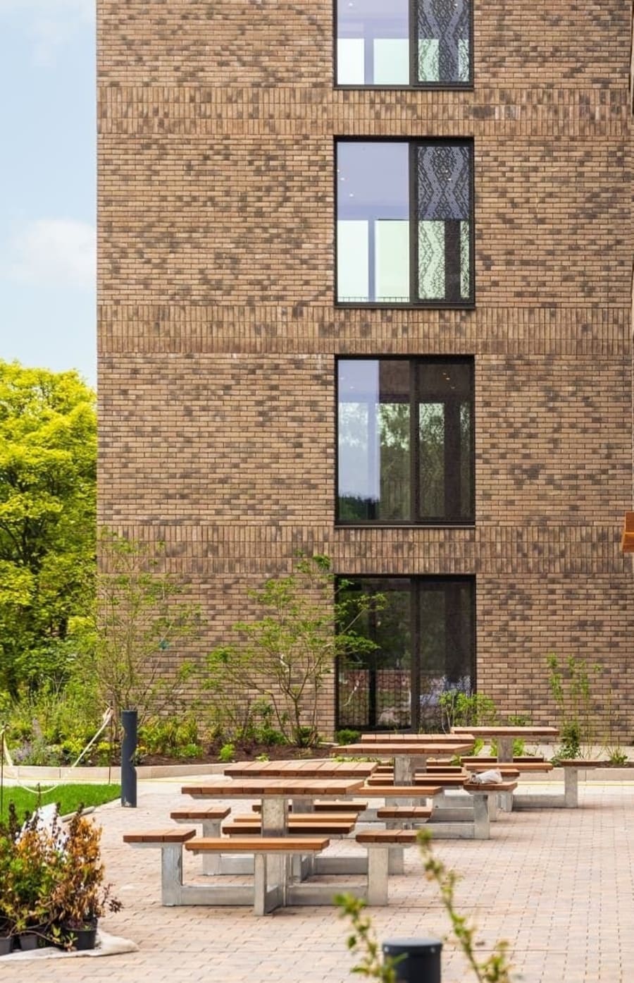 Exterior of multi-floor building with dark beige brick and large windows.