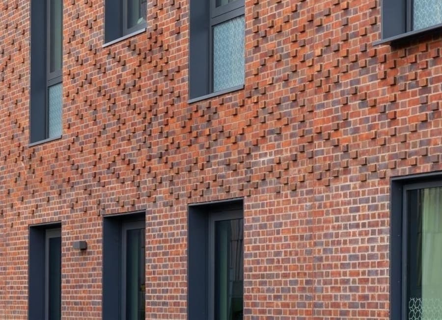 Red brick building with bricks that are designed to stick out farther than the rest.