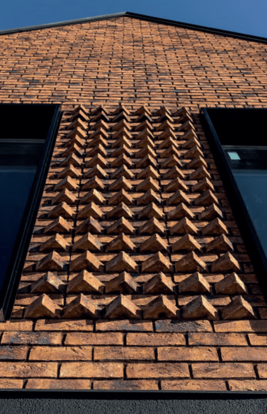 Tall brick building with patterned red brick that create triangle shapes.