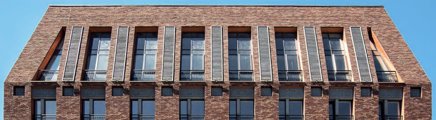 Brown brick building exterior with angled side walls and a row of windows.