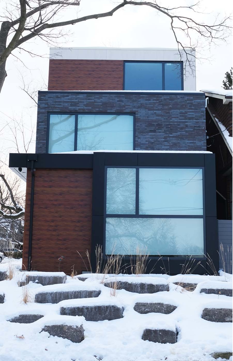 Exterior of modern home with dark grey brick and wood.