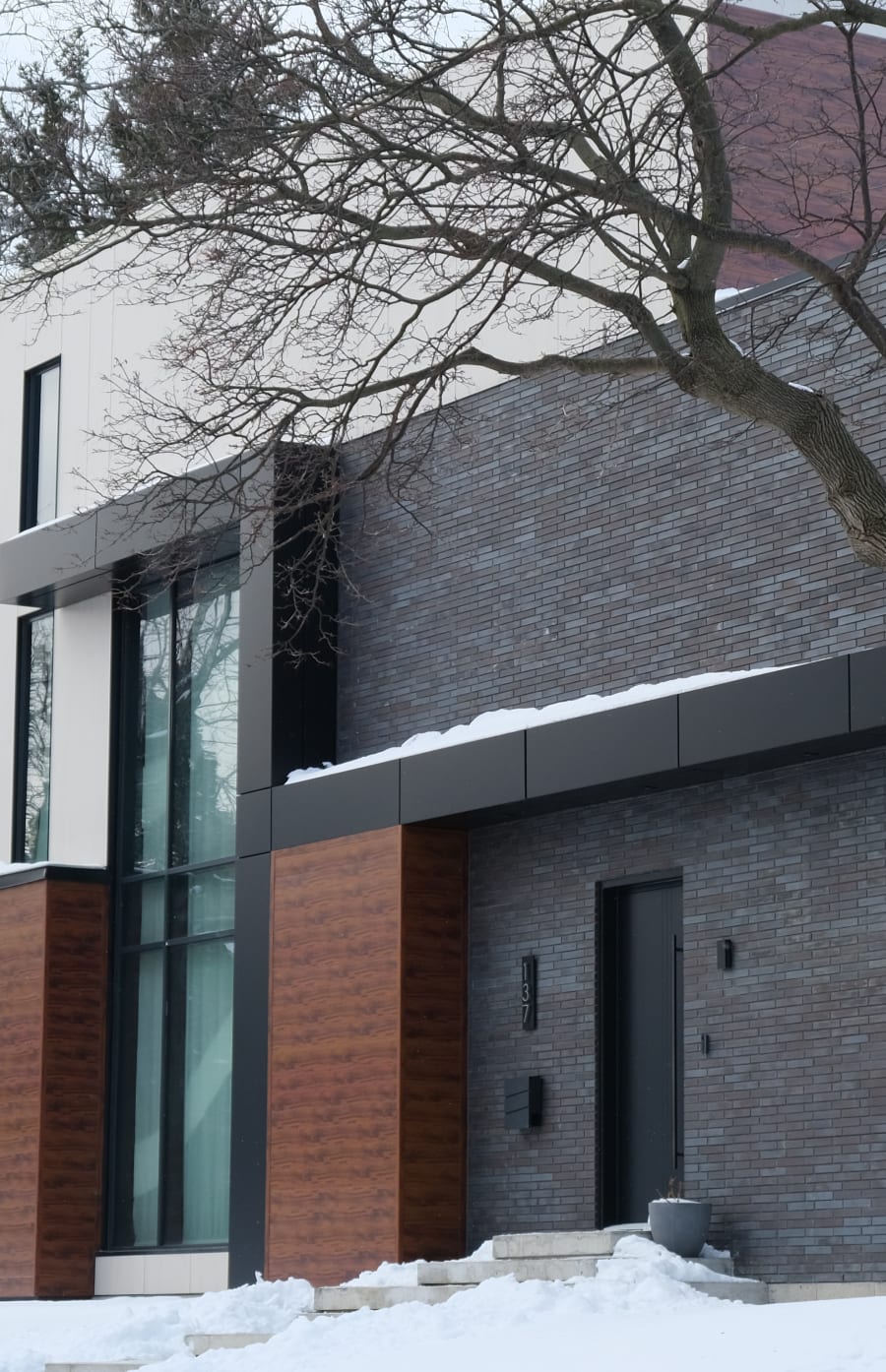 Exterior of modern home with dark grey brick and wood.