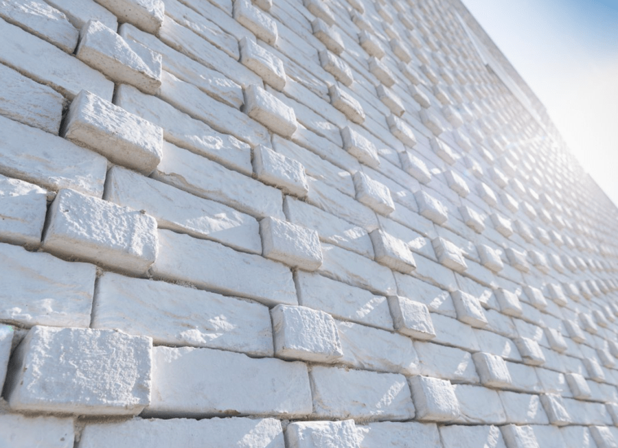 Exterior wall of a building with light beige patterned bricks.