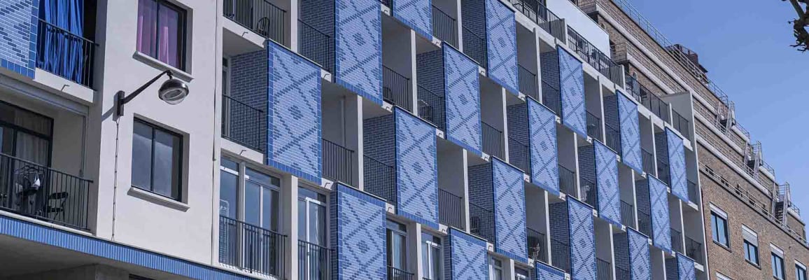 Large apartment building with blue patterned brick and multiple balconies.