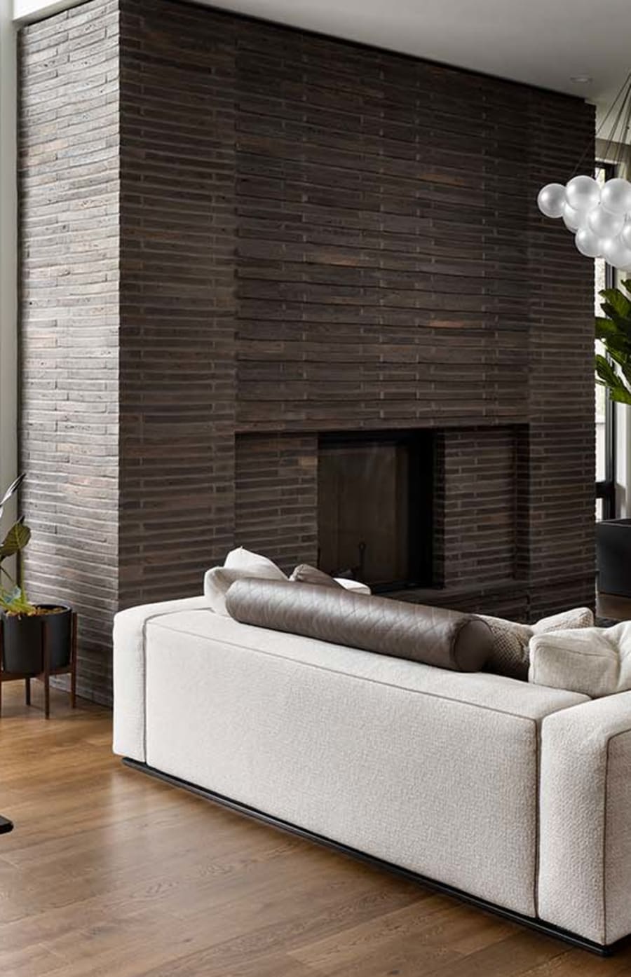 Interior brick fireplace with dark grey brick and a light beige couch next to it.