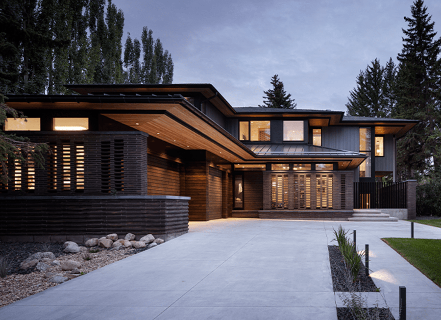 Exterior of a modern house with dark brown brick and a large white walkway.