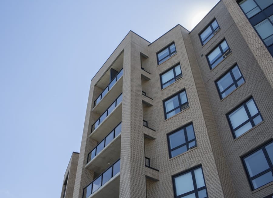 Multi-level apartment building with light beige bricks and balconies.