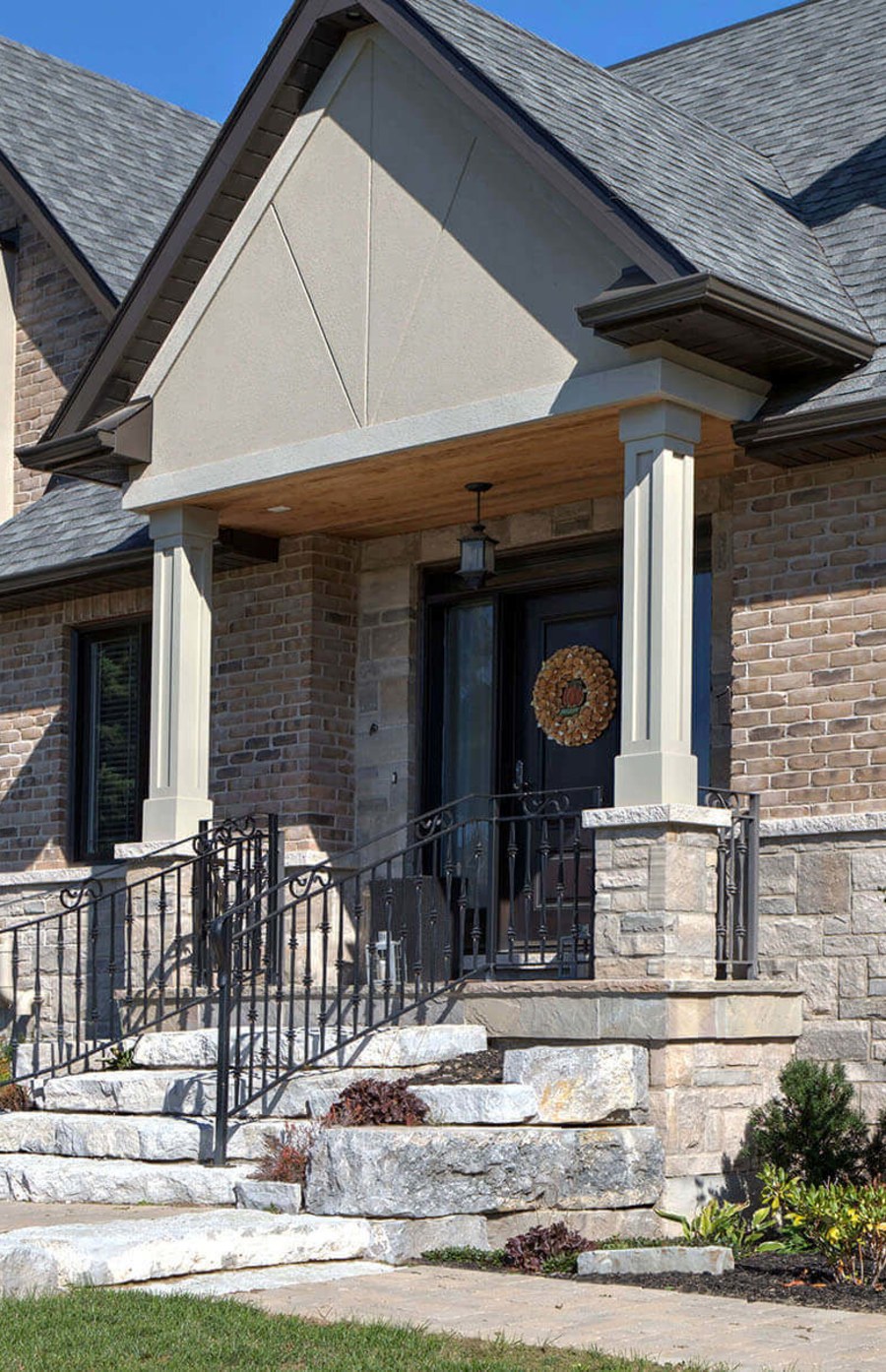 Residential home with beige brick and an iron railing on their stone steps.