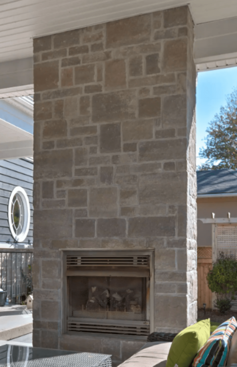 Outdoor fireplace on patio with beige stones.