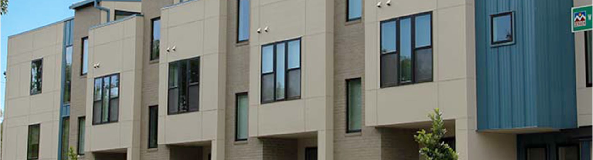 Exterior of modern beige building with black windows.