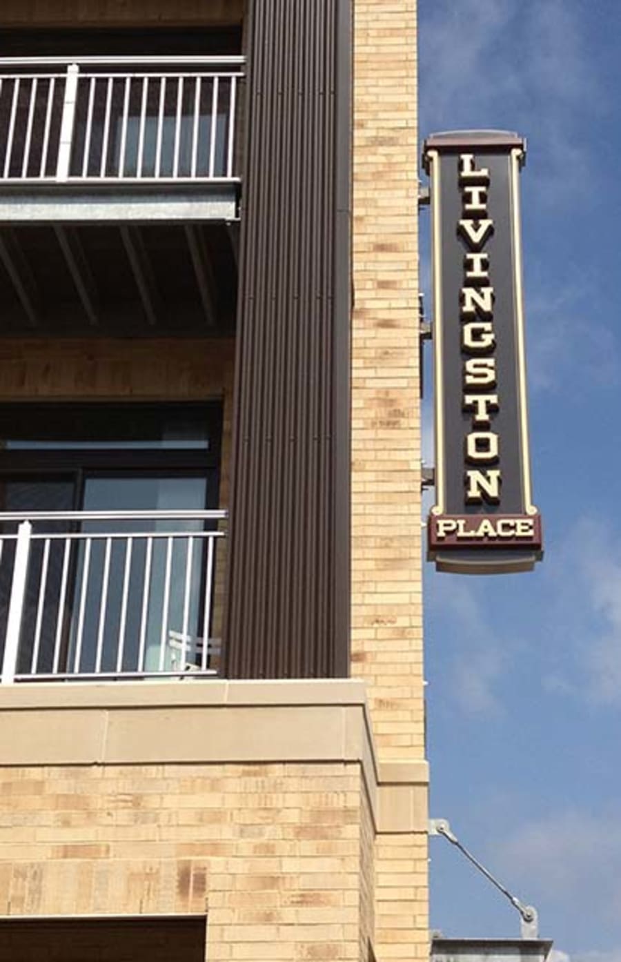 Livingston Place sign on building with beige brick and a balcony.