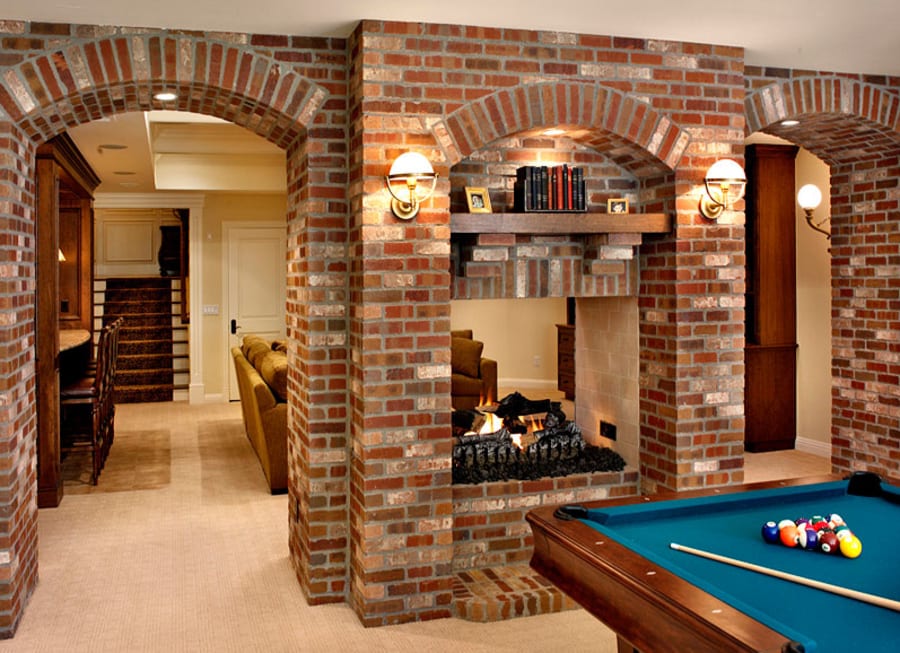 Indoor fireplace and room made of red brick, with a pool table.