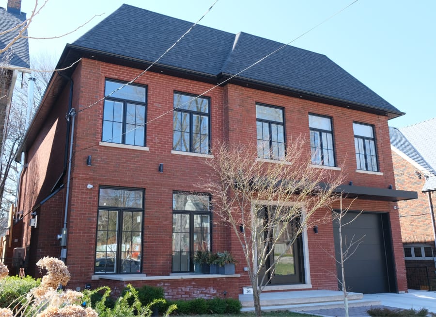 Two story residential home with red brick, large windows and a garage.