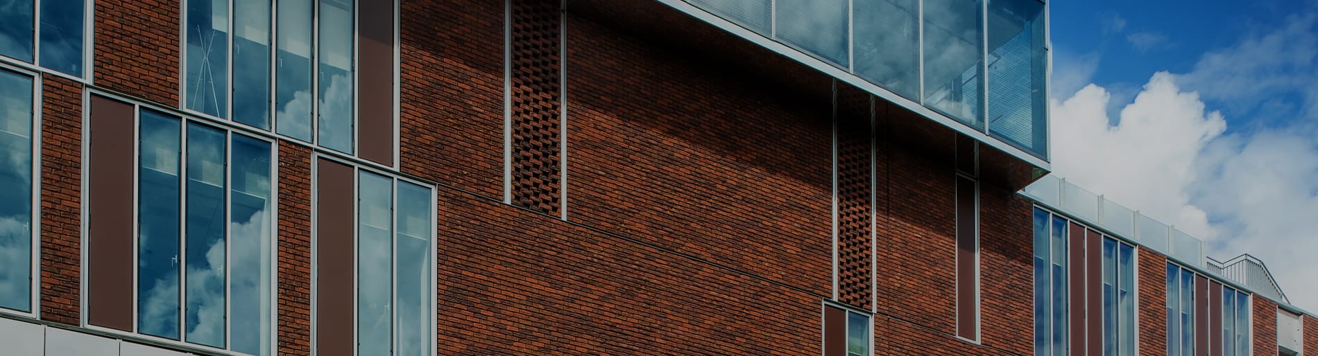 Exterior of building with small red brick and multiple floors of large windows.