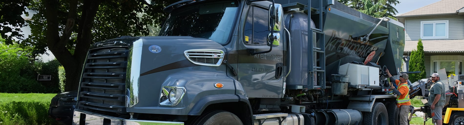 Two men with a grey concrete truck with kreitmaker logo on the side.