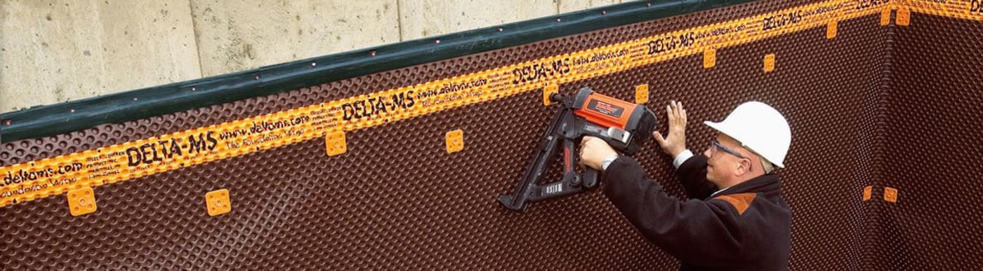 Close up of two pieces of orange piping sitting in a dirt trough in the ground.