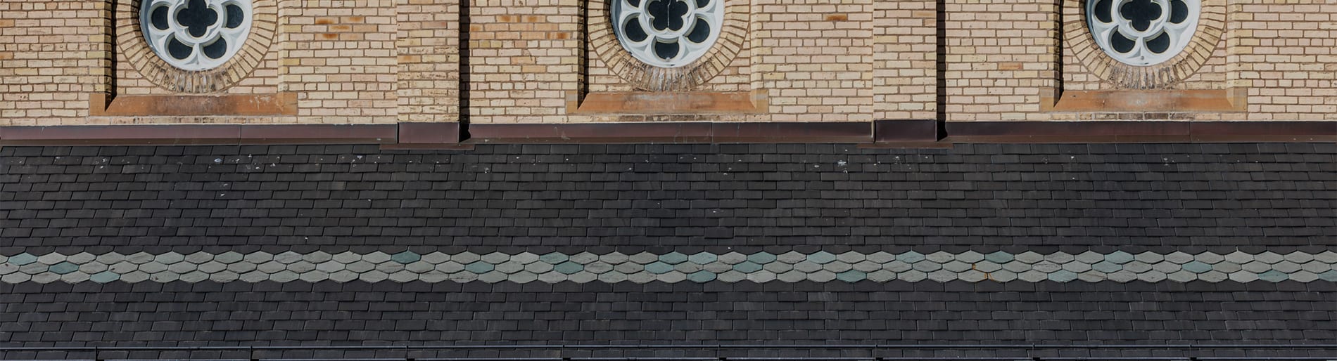 Brick buildong with dark grey brick and light beige brick and decorative windows.