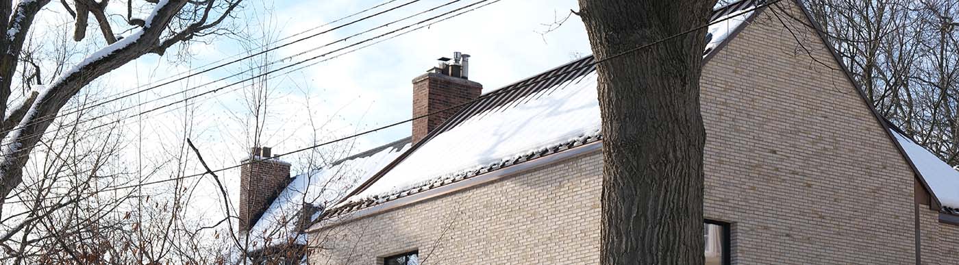 Residential home with light beige brick covered in snow.