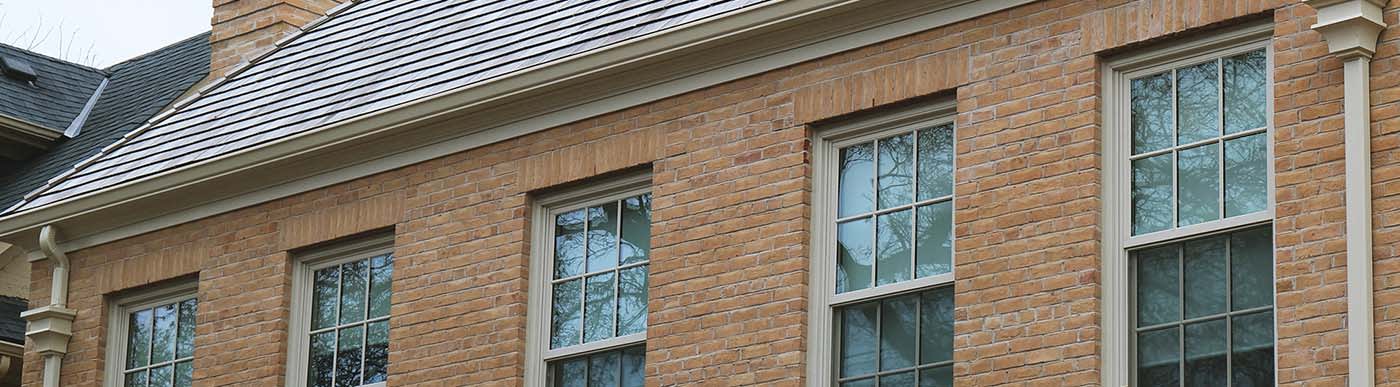 Residential building with beige brick and five windows.