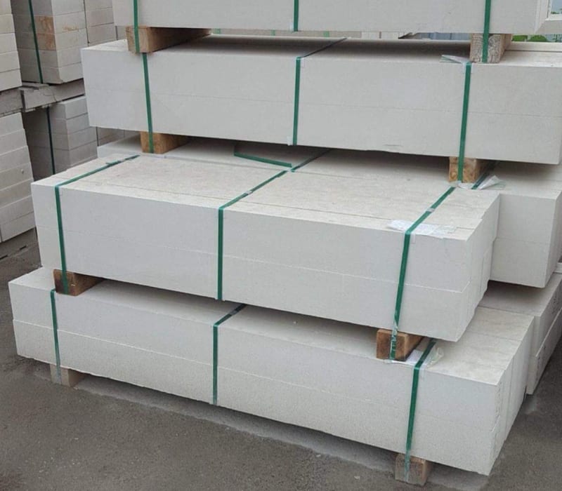 Stacks of wrapped limestone of pallets, secured with green straps.