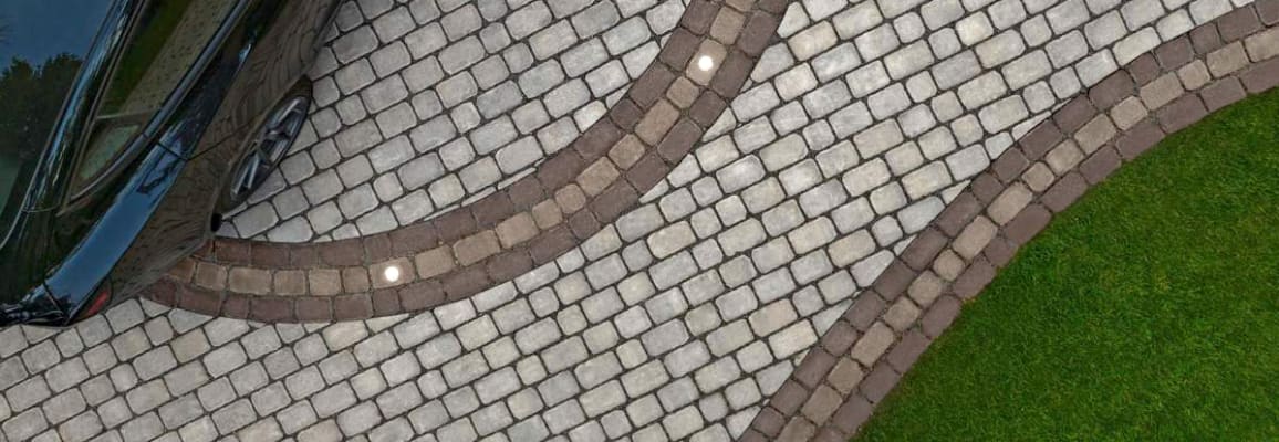 Stone driveway with grey stones and brown stones creating a pattern.