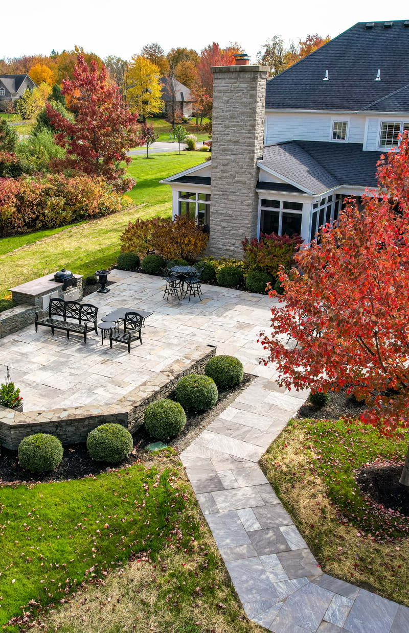 Backyard of a home with a large patio made of pavers and flagstone.