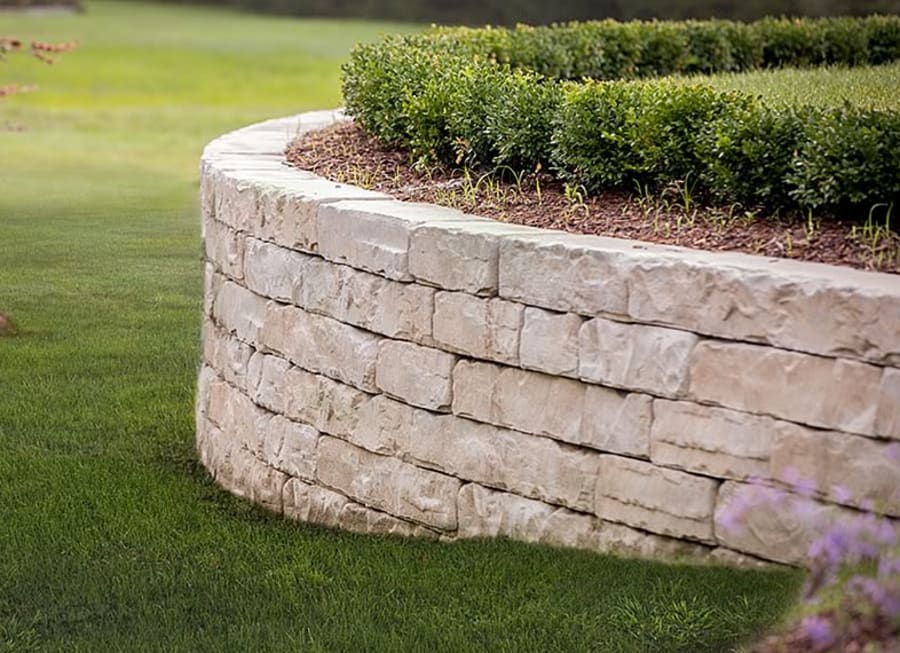 Edge of a garden wall with grey pavers and flagstone.