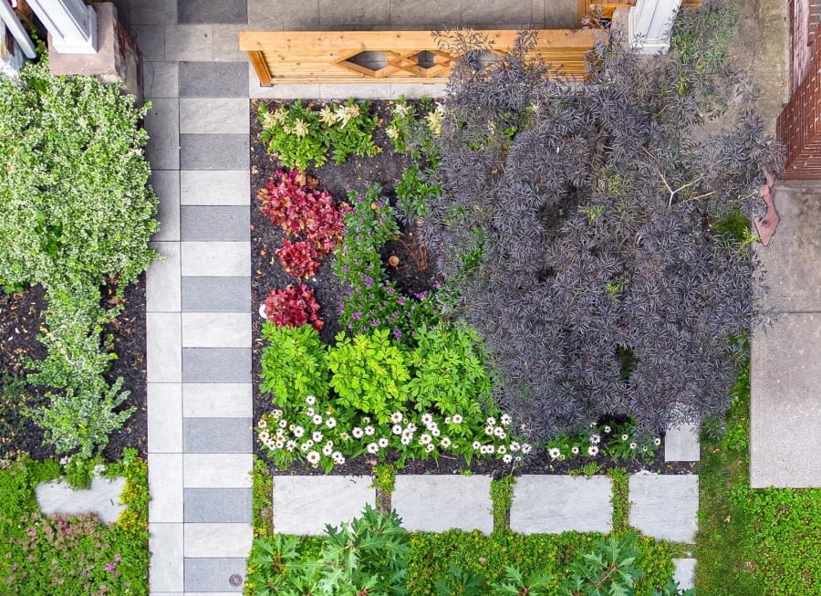 Patterned patio stones surrounded by plants and grass.