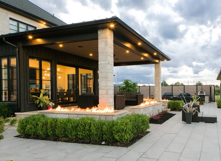 Exterior fire place feature with bushed and light beige stone pillar.