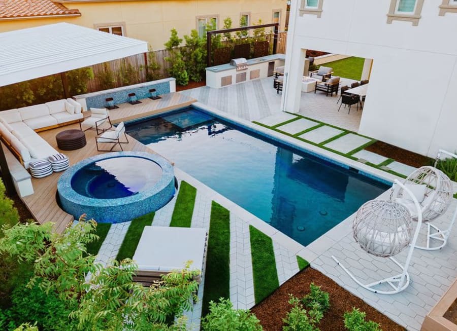 Backyard patio with a pool, stone designs, a hot tub and seating.