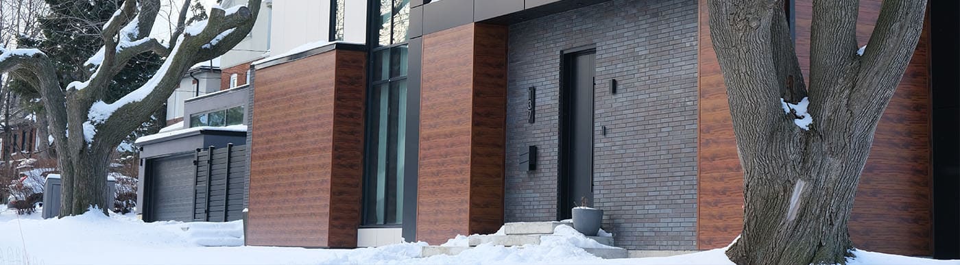 Modern residential home with dark grey brick and wood panels.