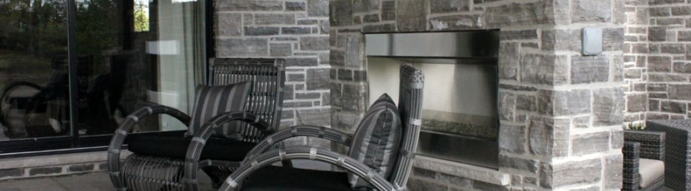 Exterior stone stairs with foliage on either side, multiple lights and a beige garage door to the right of the stairs.