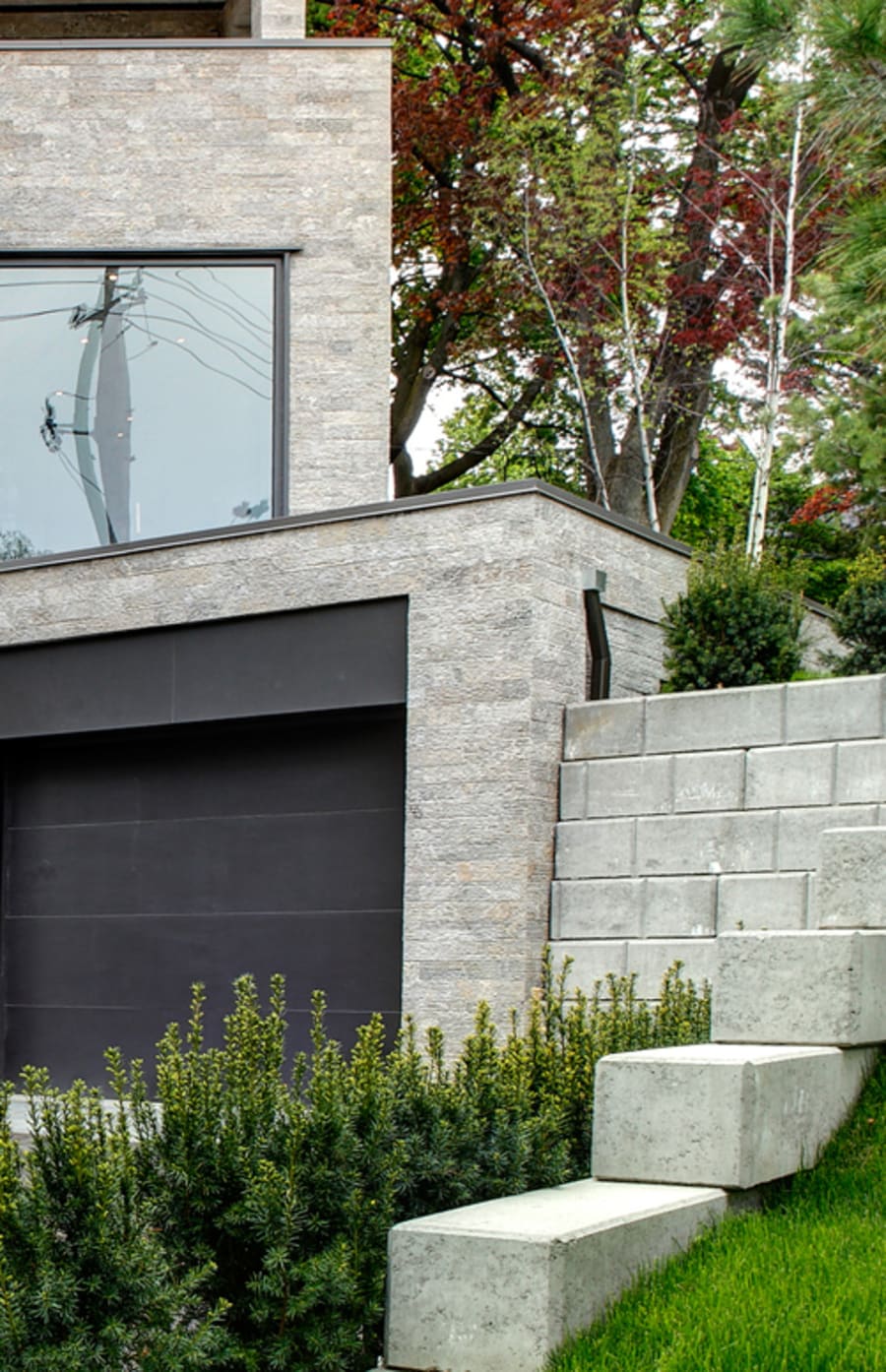 Light grey house with garage door and retaining wall.