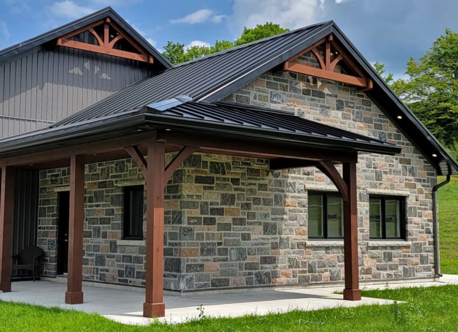 Exterior of home with multi-colour grey and brown brick with wood pillars.