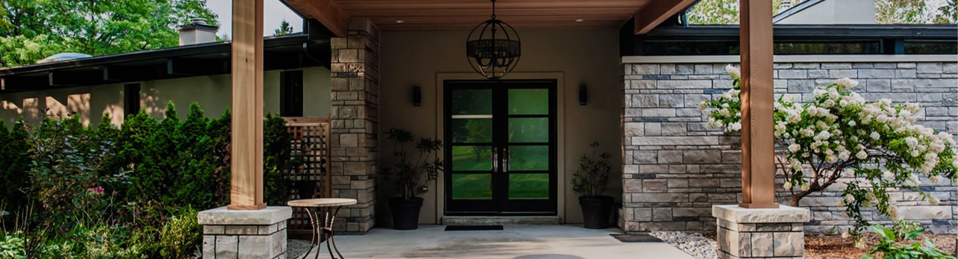 Exterior of a house with pillars and grey wall stone.