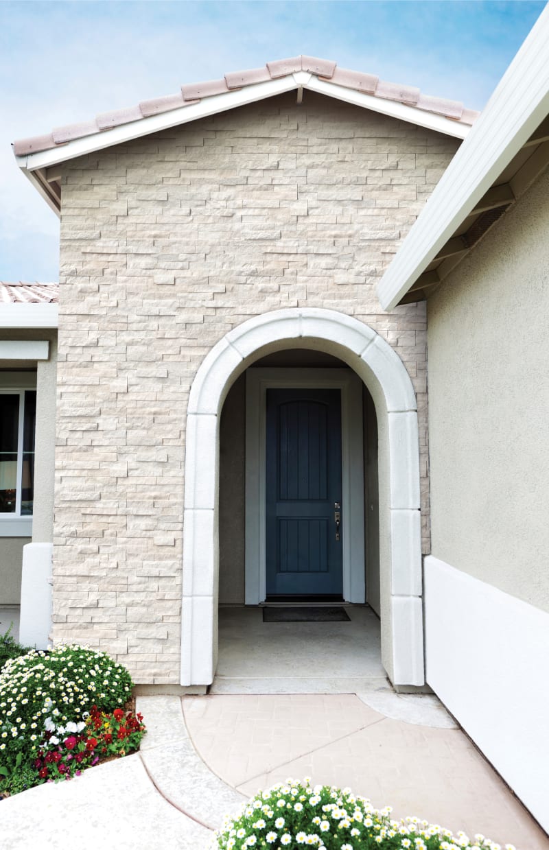 Arched entrance way to a white brick house