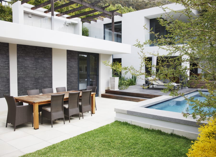 Outdoor patio with large white patio stone, an in-ground pool and an outdoor dining table